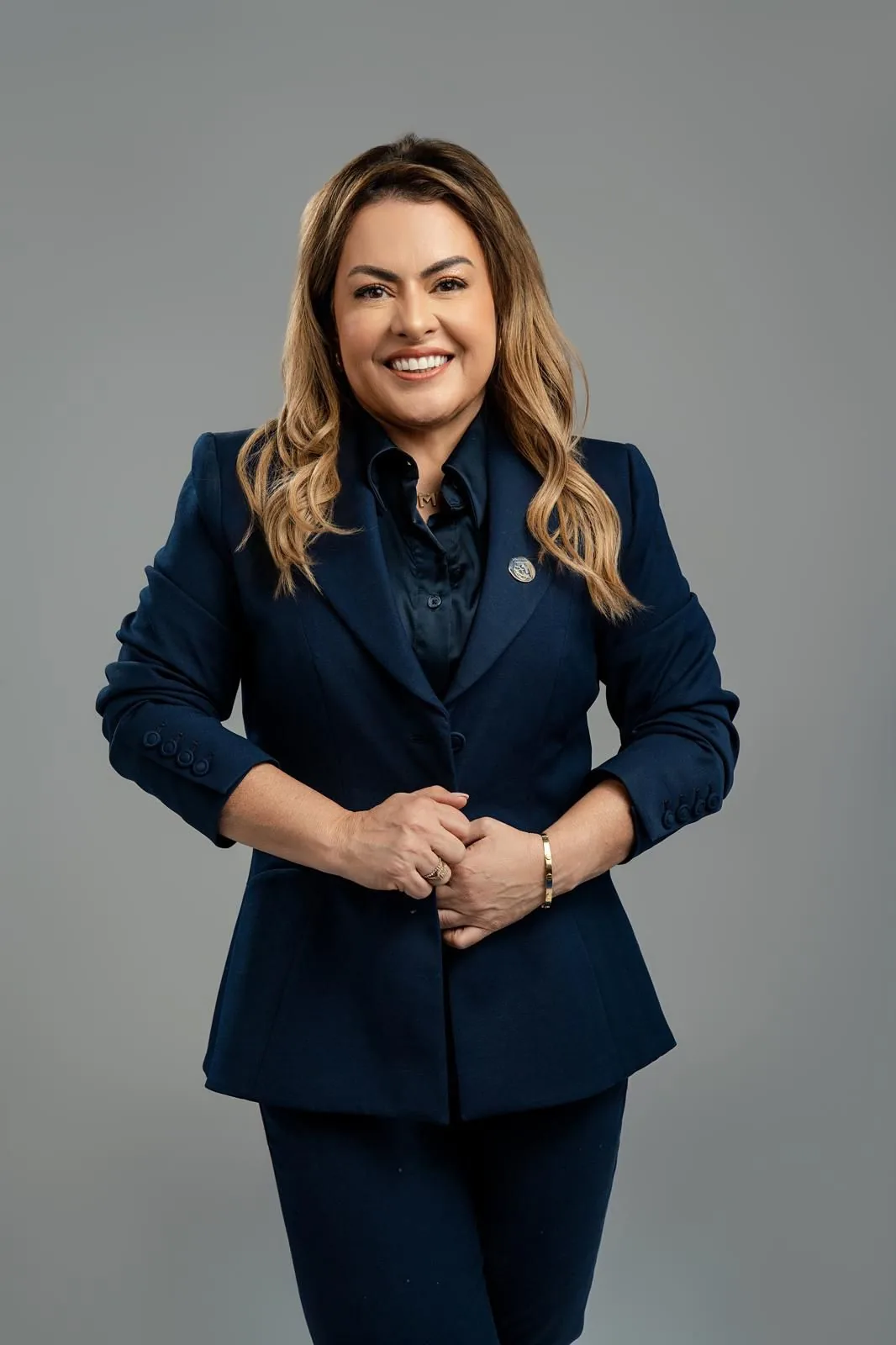 Mildred López sonriendo, con traje azul marino y las manos entrelazadas.